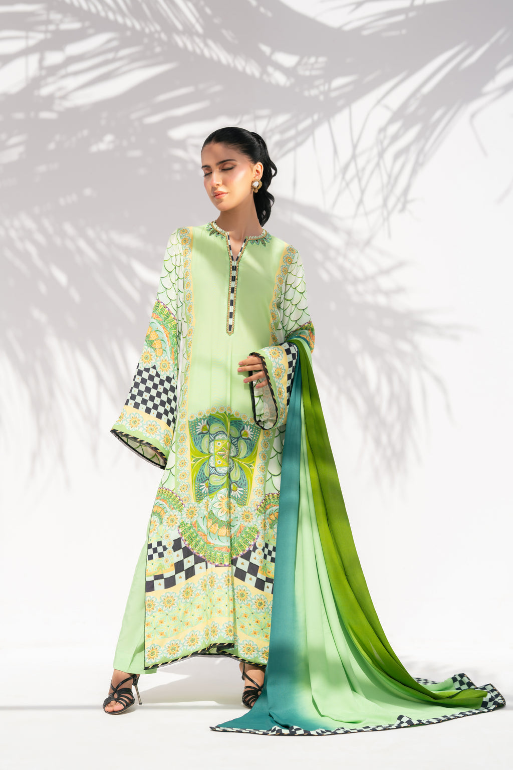 Woman wearing a green and white patterned dress with a matching scarf against a white background