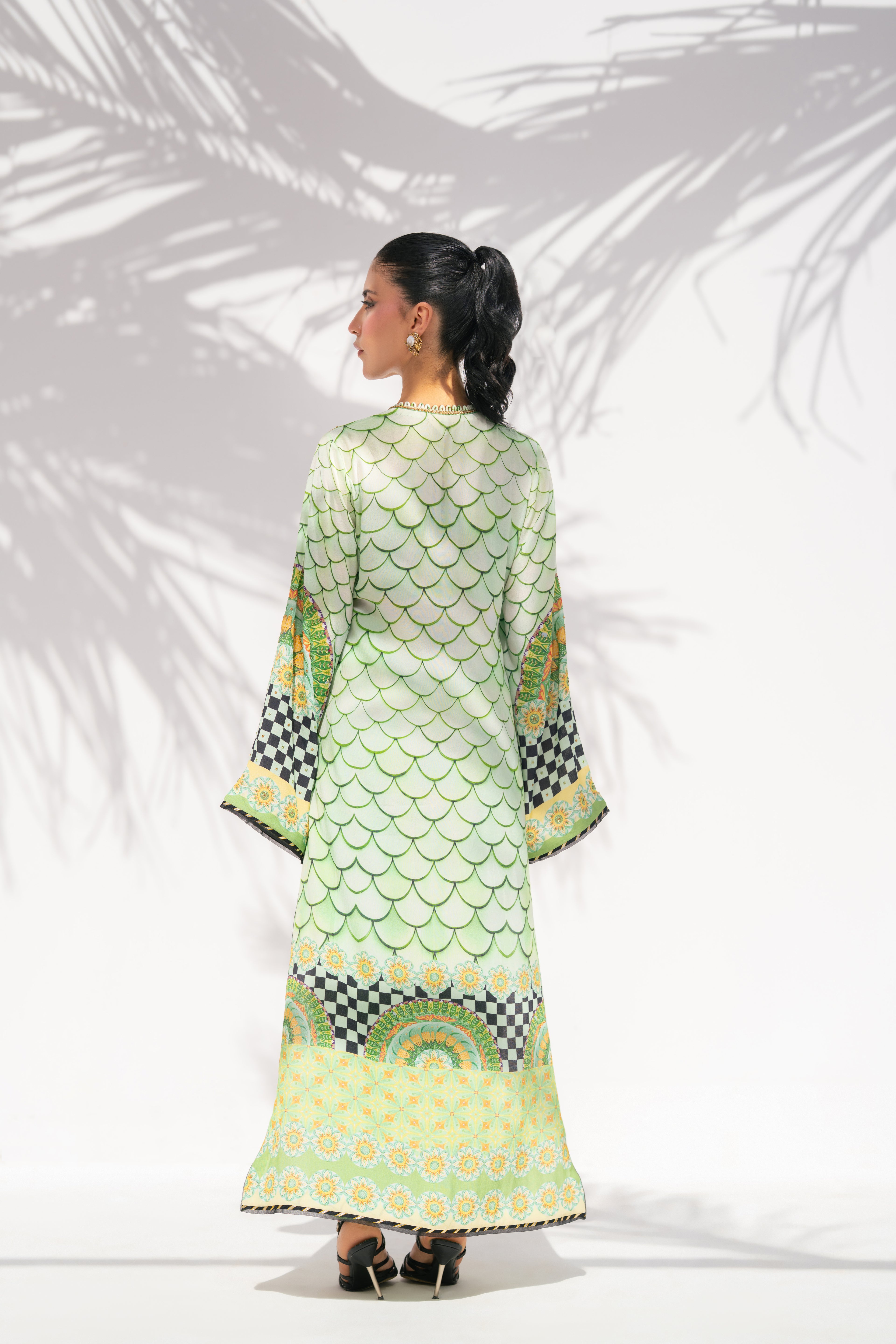 Woman wearing a green and black patterned dress with a white background
