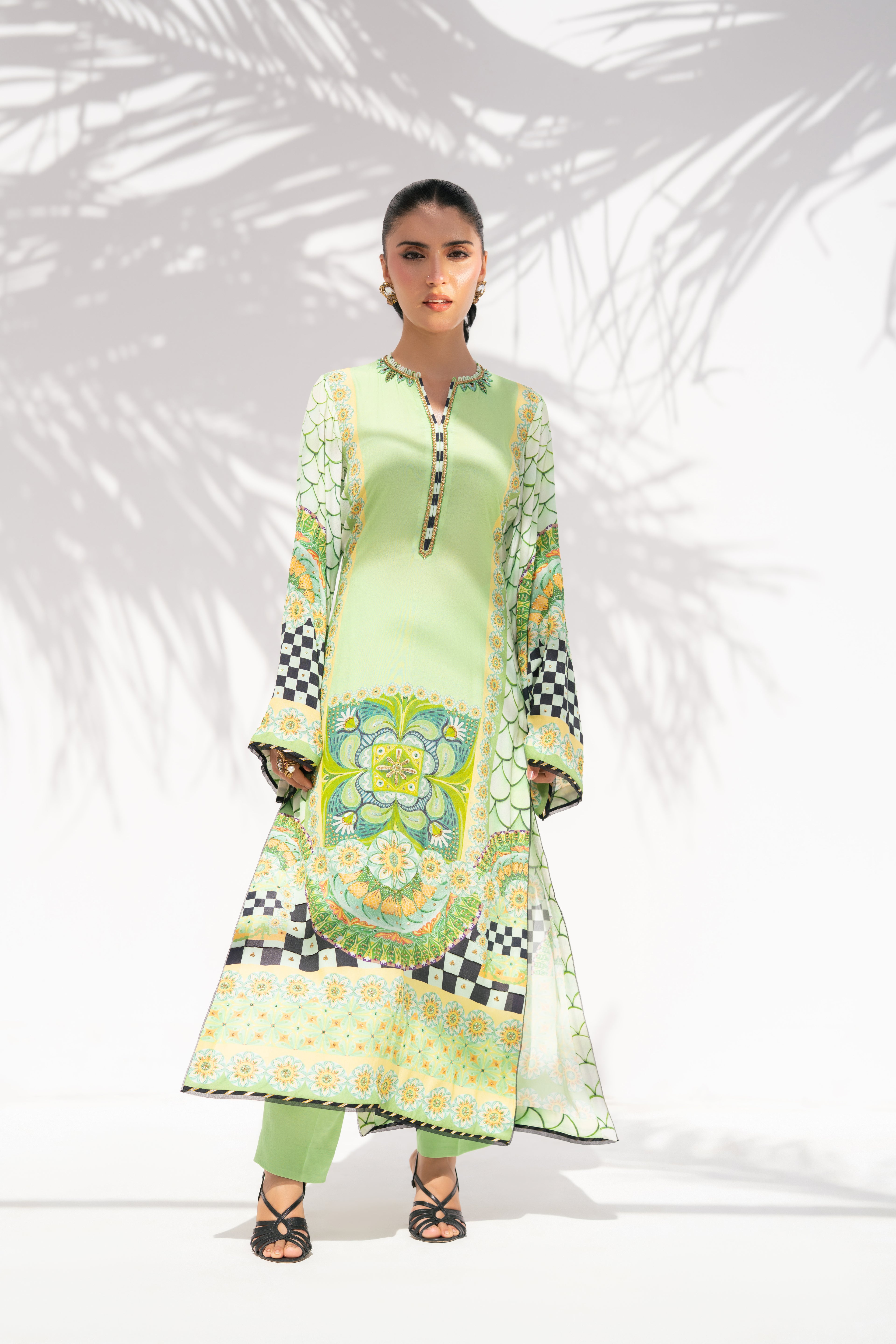 Woman wearing a green traditional outfit with floral patterns on a white background