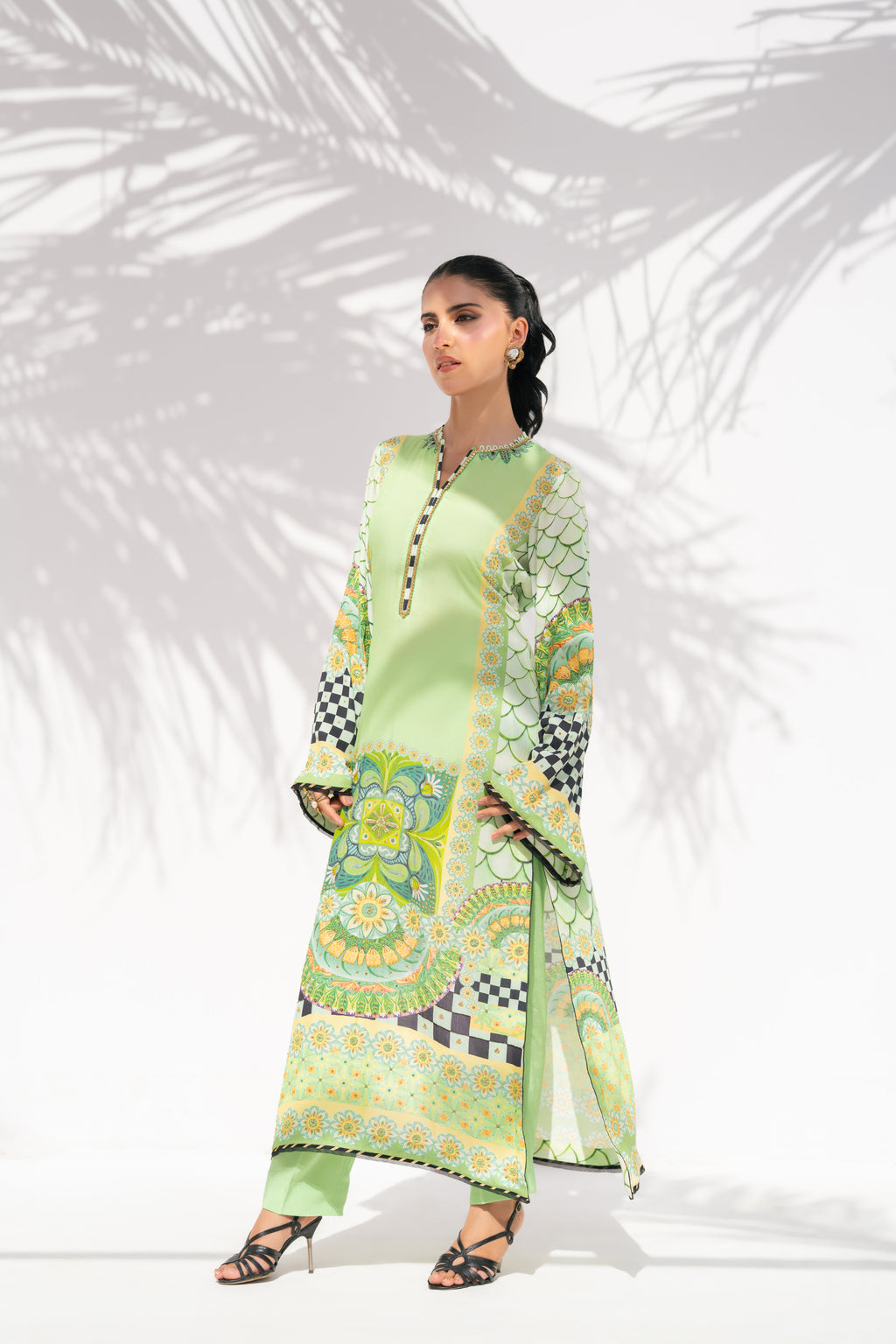 Woman wearing a green patterned outfit against a white background