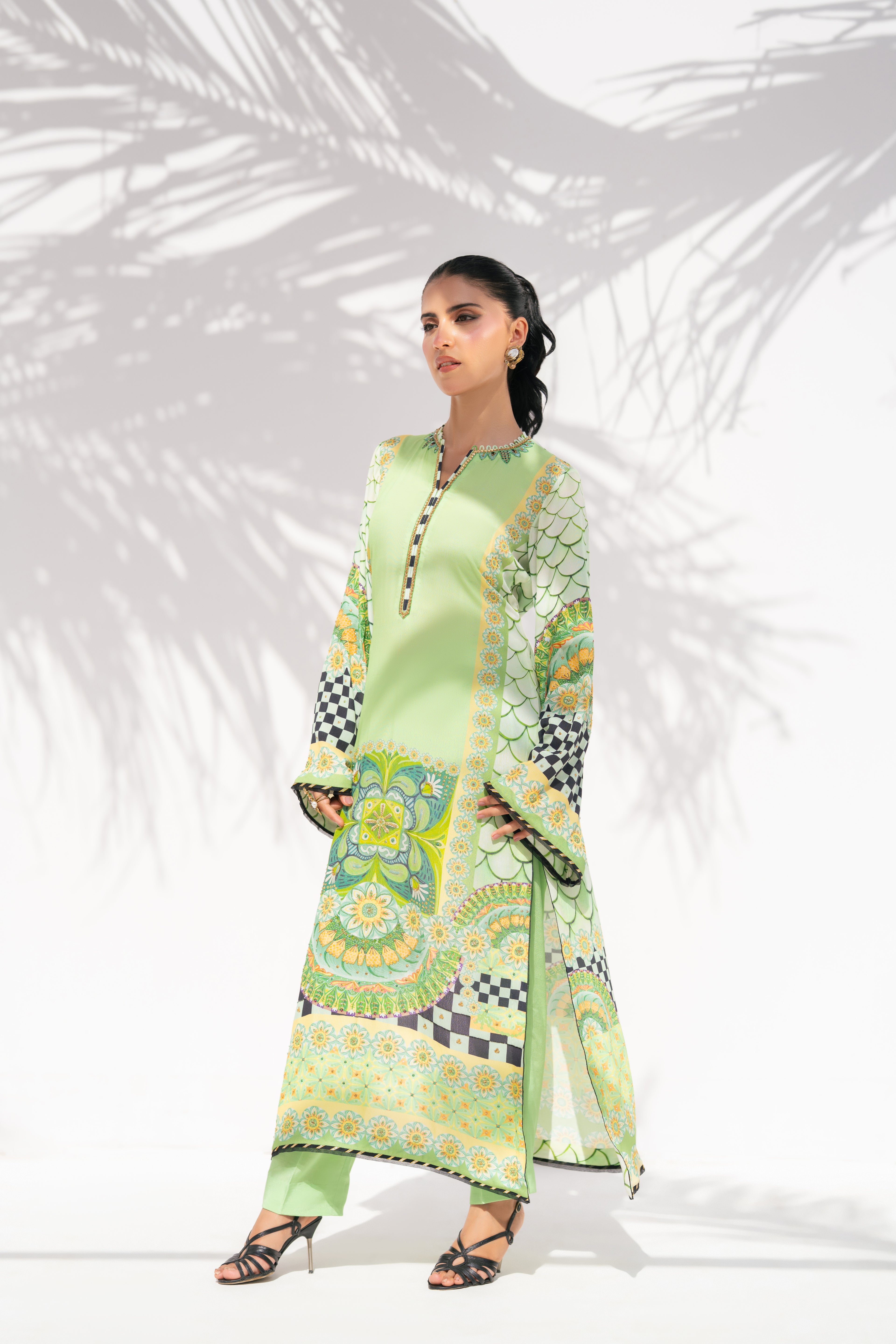 Woman wearing a green patterned outfit against a white background