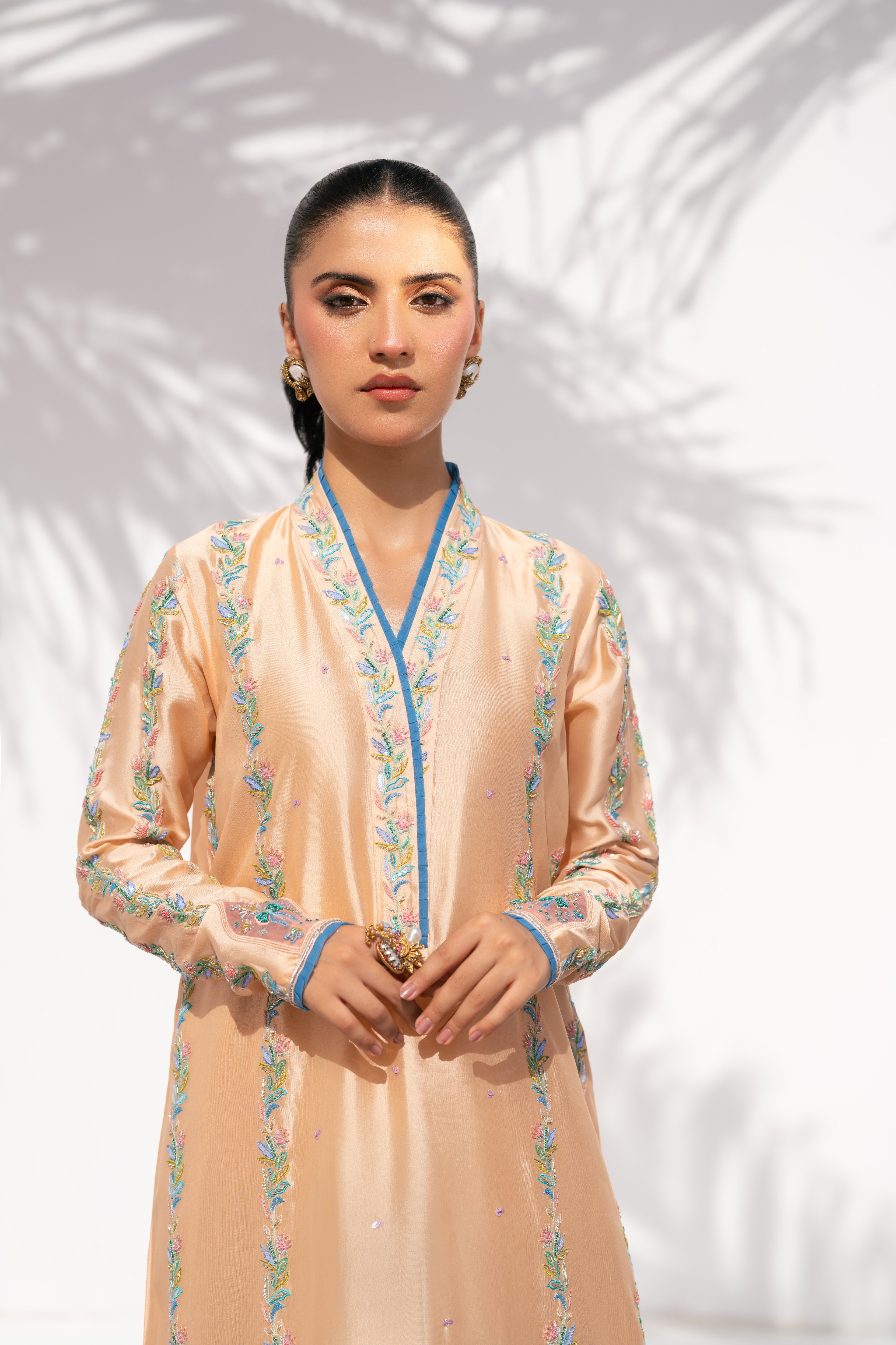 Woman wearing a peach-colored traditional outfit with blue accents against a white background