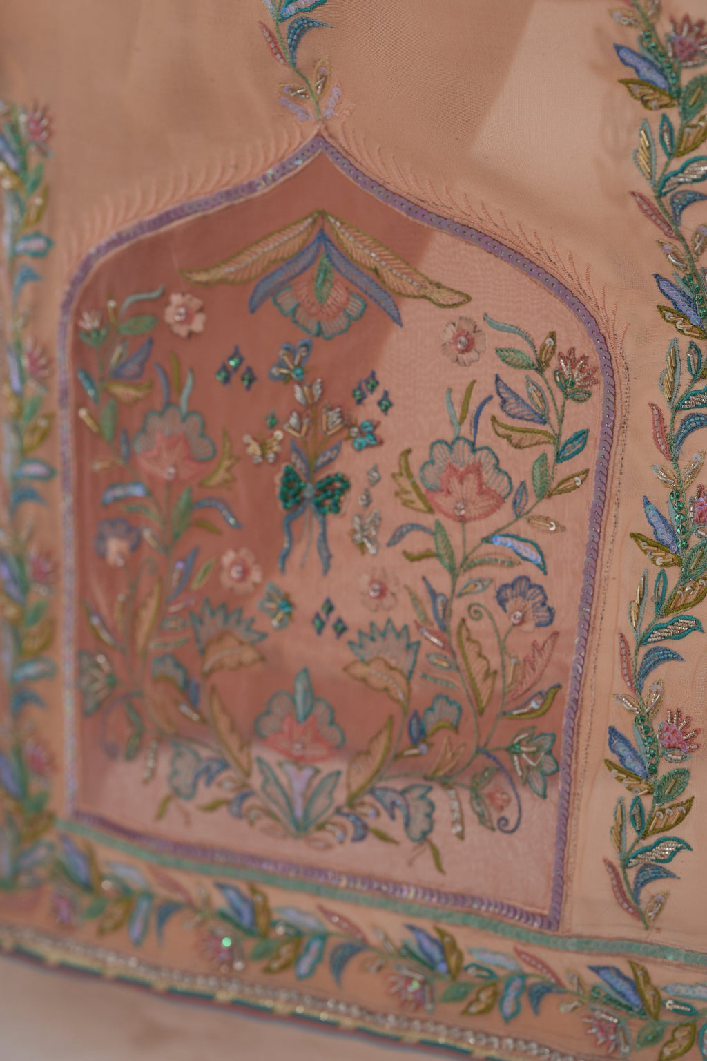 Close-up of a traditional embroidered garment with intricate patterns on a light background