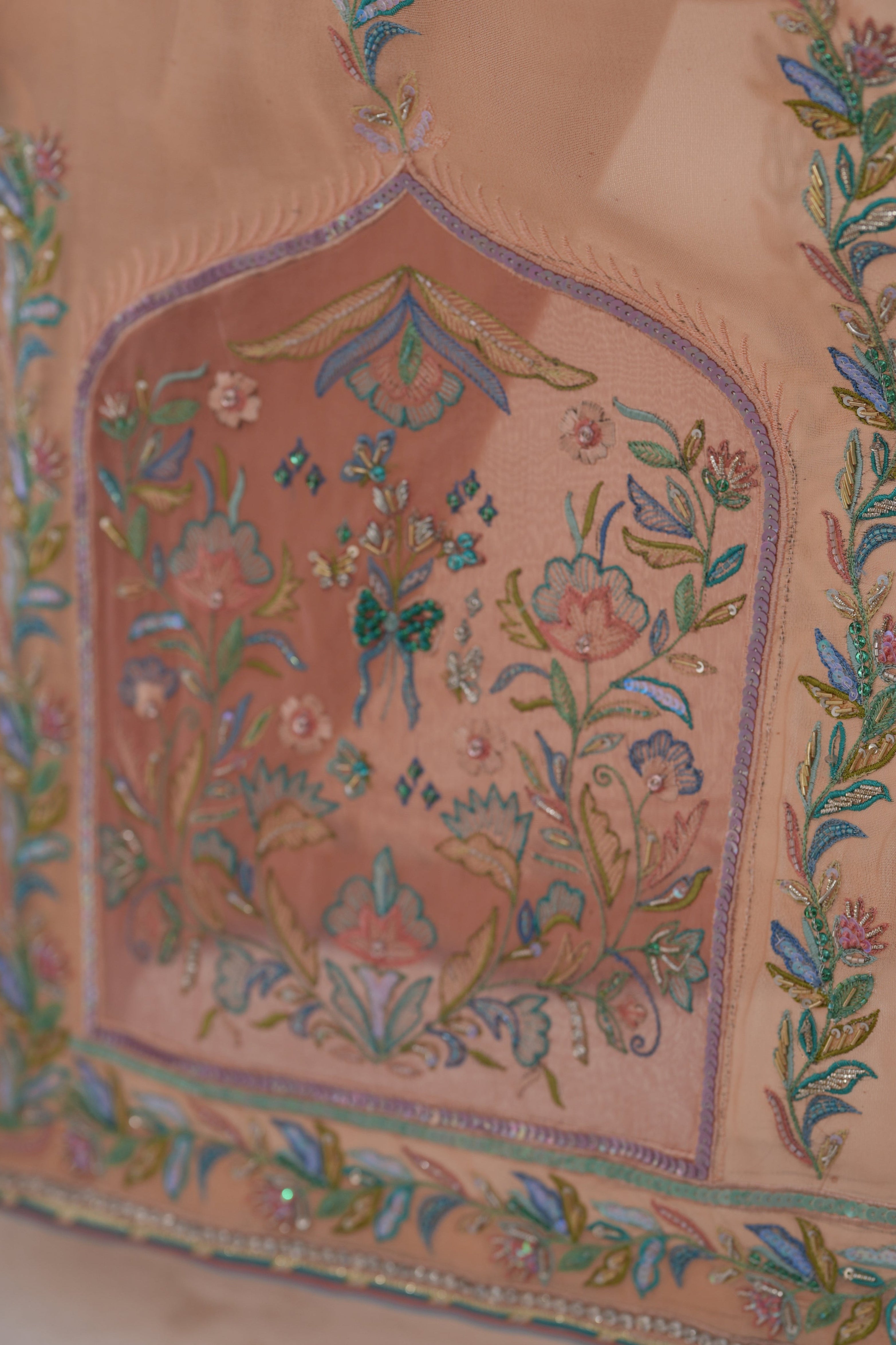 Close-up of a traditional embroidered garment with intricate patterns on a light background