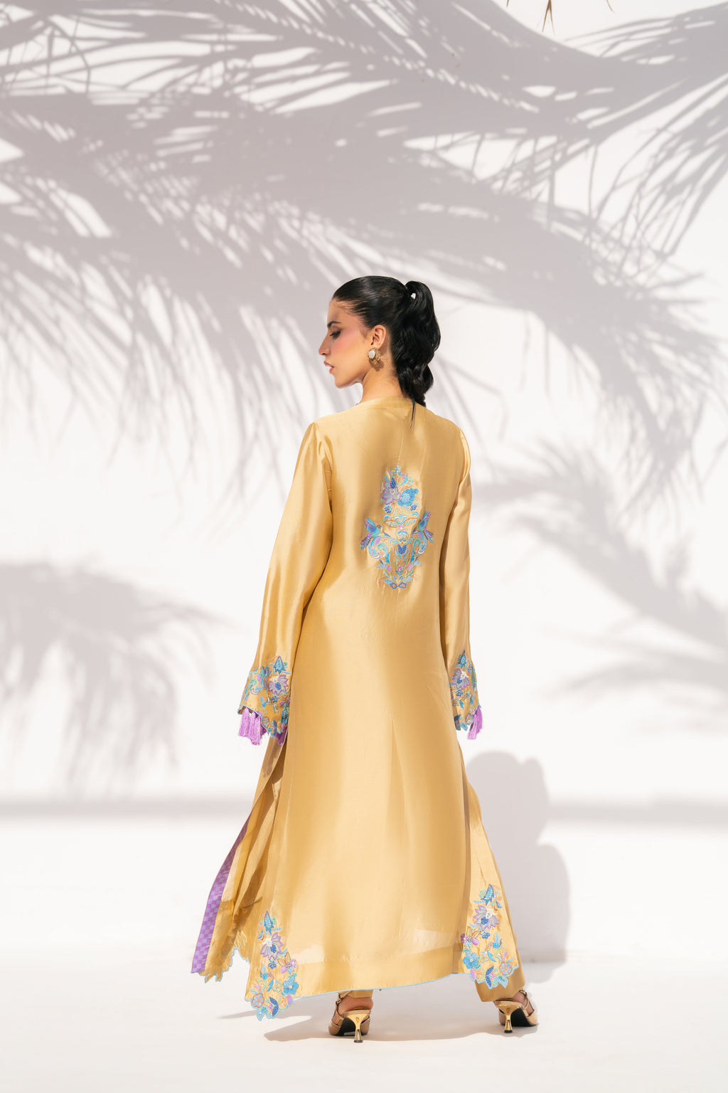 Woman wearing a yellow dress with floral patterns in a minimalistic setting