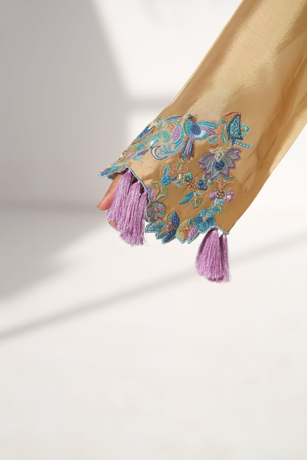 Decorative kaftan with floral patterns and tassels on a light background