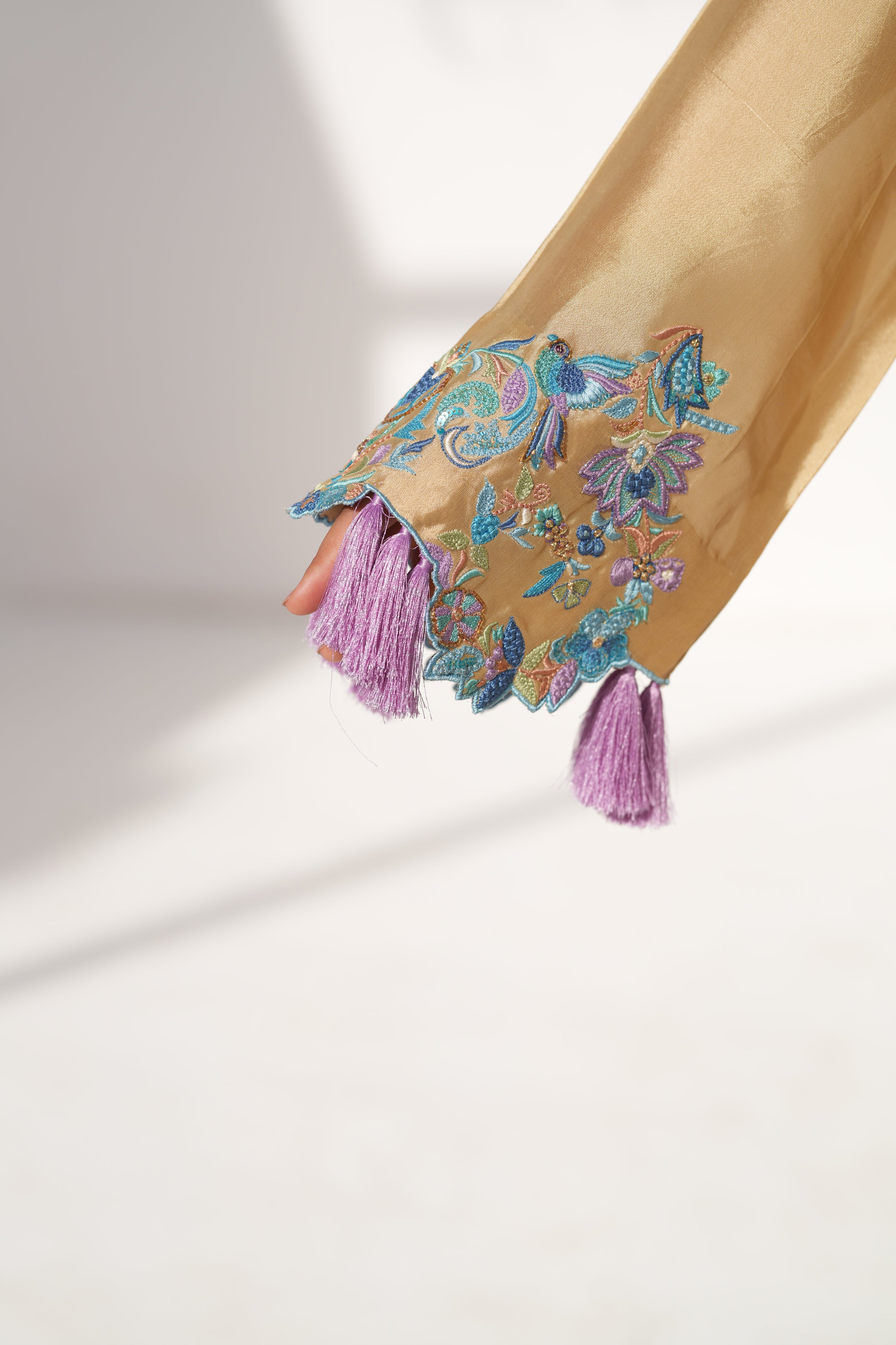 Decorative kaftan with floral patterns and tassels on a light background